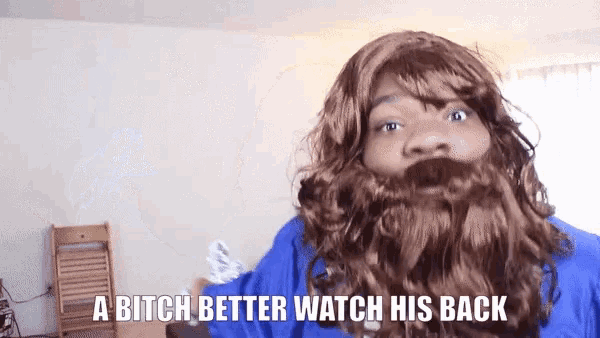 a man with a beard is wearing a blue shirt and says a bitch better watch his back