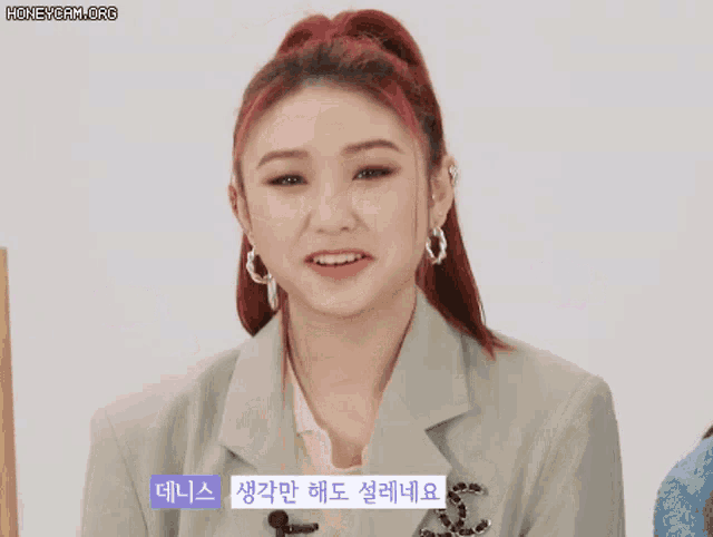 a woman with red hair is wearing a jacket and earrings .