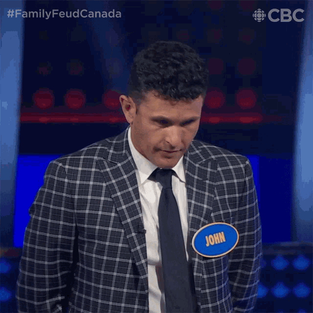 a man wearing a plaid suit and tie has a name tag that says john