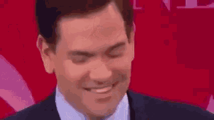 a man in a suit and tie is standing in front of a red background .