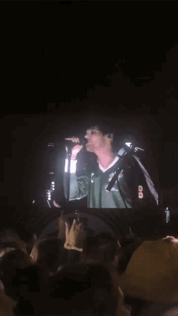 a man singing into a microphone in front of a crowd with a sign that says ' 00 ' on it