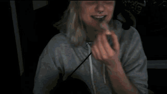 a woman wearing headphones and a nose ring smiles for the camera