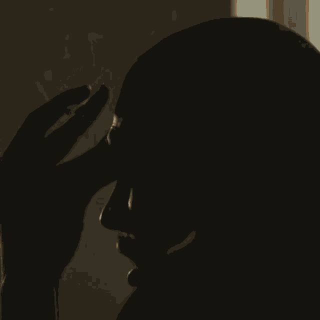 a silhouette of a man 's head with his hand on it .