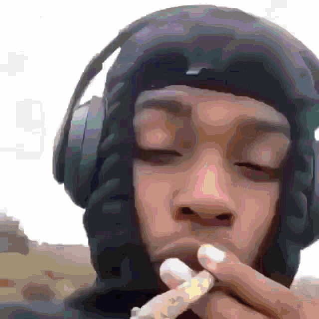 a man wearing headphones and a helmet smoking a cigarette