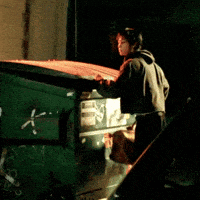 a man standing next to a green dumpster with the letter k written on the side