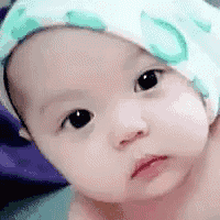 a close up of a baby wearing a hat and looking at the camera .