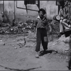 a black and white photo of a young boy walking on a dirt road