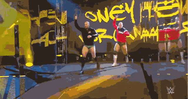 two wrestlers on a stage with the word sney written on the wall
