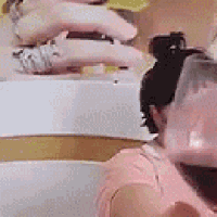 a woman in a pink shirt is sitting in a bathtub with a glass of water in her hand .