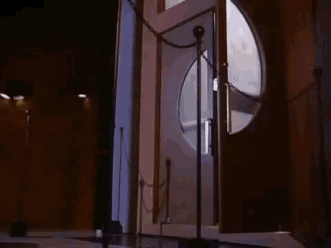 a door is chained to a pole in a dark room with a microphone in front of it .