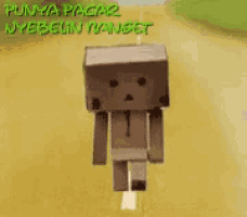 a cardboard box figure is walking down a road with the words punya pacar nyebelin yanset written on it