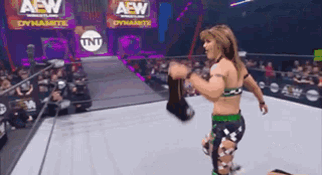 a woman is standing in a wrestling ring with a sign that says aew on it