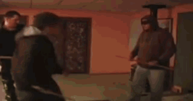 a group of people are standing next to each other in a room holding sticks .