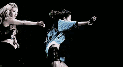 two women are dancing together on a stage in a dark room .