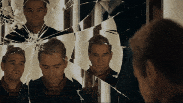 a man looking at himself in a broken mirror