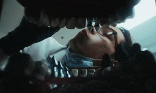 a dentist examines a model of a person 's teeth with a magnifying glass