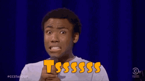a man is holding a microphone and making a funny face while saying tssss .