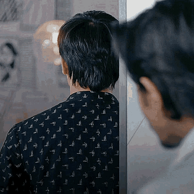 a man in a black shirt is standing in front of a mirror