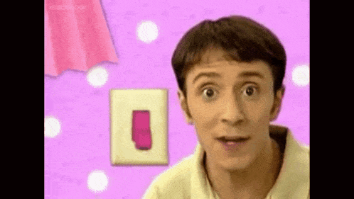 a man is standing in front of a pink wall with a light switch and a pink towel .