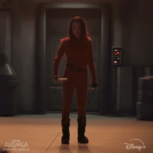 a woman is holding a green lightsaber in front of a disney logo