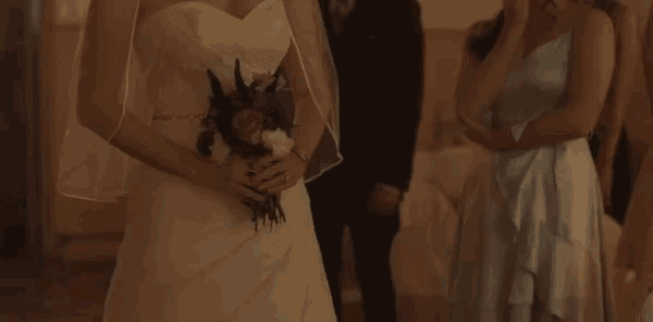 a bride in a wedding dress holds a bouquet of flowers in her hands
