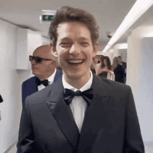 a man in a tuxedo and bow tie is laughing