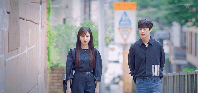 a man and a woman standing next to each other on a sidewalk .