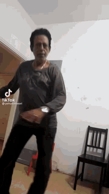 a man is dancing in a room with a chair and a chair in the background .