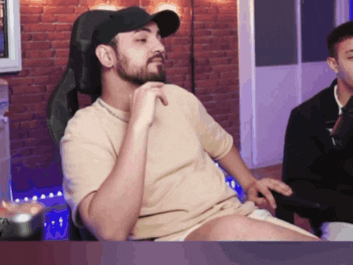 a man with a beard is sitting in a chair with his legs crossed