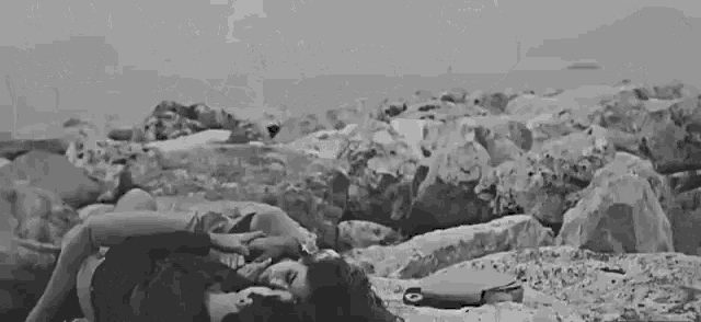 a black and white photo of a woman laying on the beach .