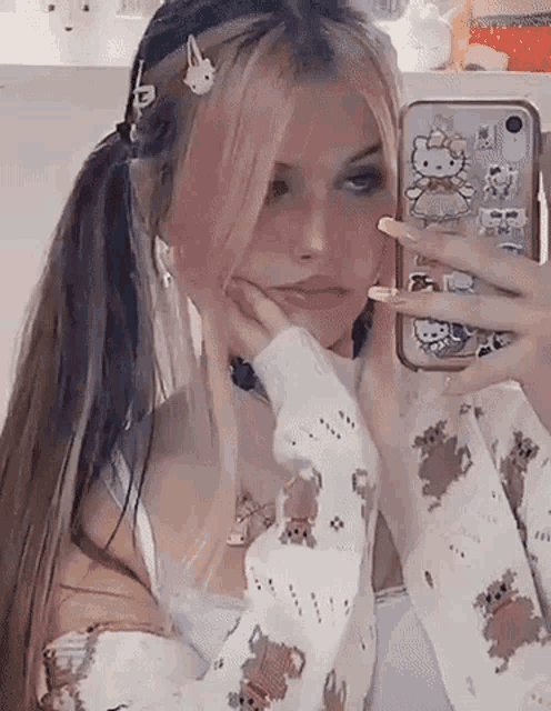a girl with pink hair is taking a selfie in front of a mirror .