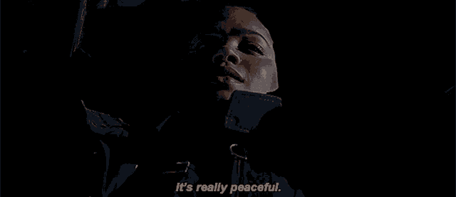 a woman in a black jacket is laying down in the dark and says it 's really peaceful .