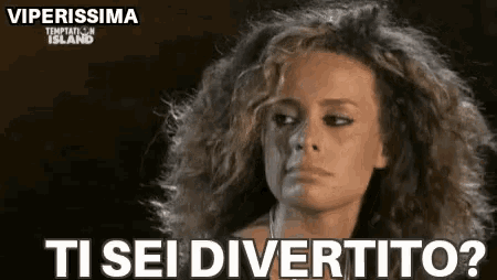 a woman with curly hair is looking at the camera with the words `` ti sei divertito '' written on the bottom .