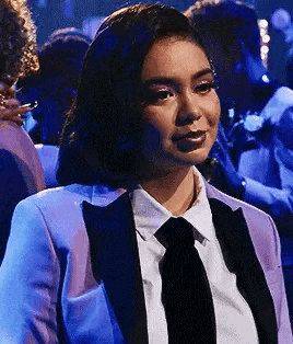 a woman in a suit and tie is sitting in a crowd of people .