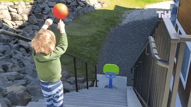 a child is playing with a ball on a set of stairs with the letters th visible
