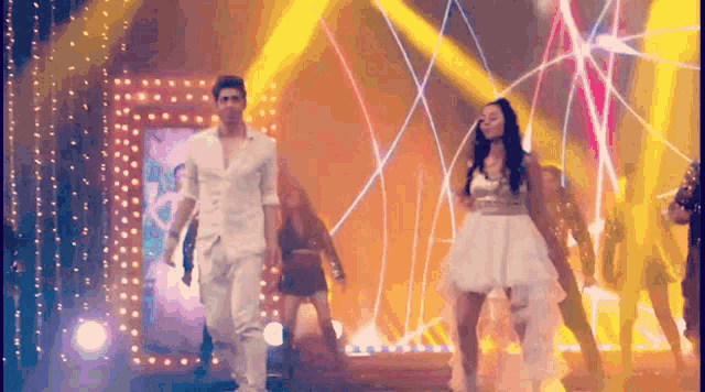 a man in a white shirt and a woman in a white dress are dancing on a stage