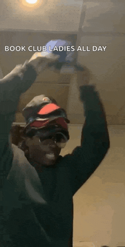 a man wearing a hat and sunglasses is holding a cell phone in his hands .