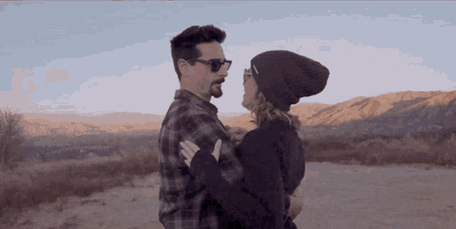 a man is holding a woman in his arms and the woman is wearing a black beanie