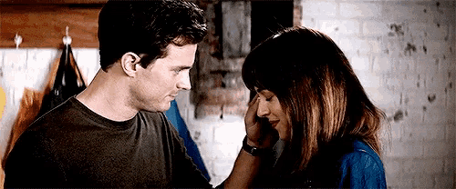 a man and a woman are looking into each other 's eyes . the woman is touching the man 's face .