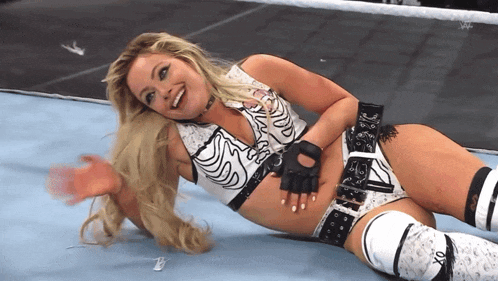 a woman in a wrestling outfit is laying on the floor smiling