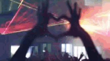 a group of people are making a heart shape with their hands in front of a crowd .
