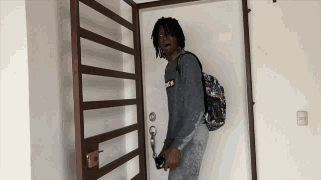 a man with dreadlocks is standing in front of a door with the word nike on his shirt