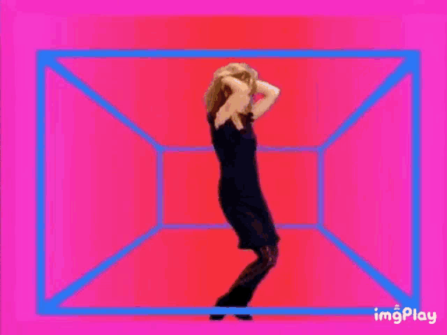 a woman in a black dress is dancing in a pink and yellow cube .