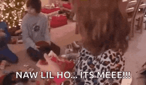 a group of people are sitting on the floor opening christmas presents and a woman is holding a christmas present .