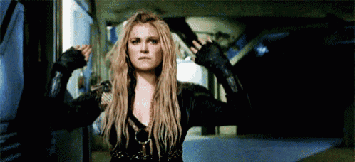a woman is standing in a dark room with her arms outstretched and a gun in her hand .