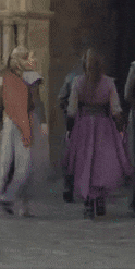 a woman in a purple dress is standing next to a man in a white coat .