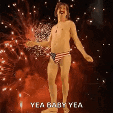 a shirtless man in a bikini is dancing in front of fireworks .