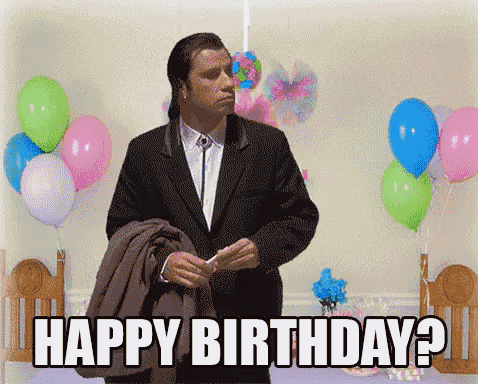 a man in a suit stands in front of balloons and says happy birthday ?