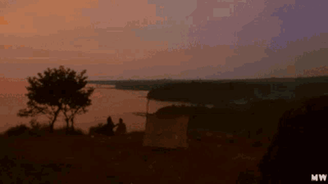 a sunset over a lake with a tent in the foreground and mw on the bottom