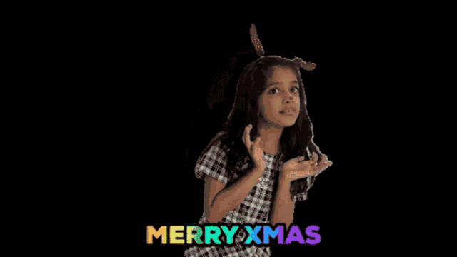 a little girl wearing reindeer antlers and a red nose is dancing and singing merry xmas .
